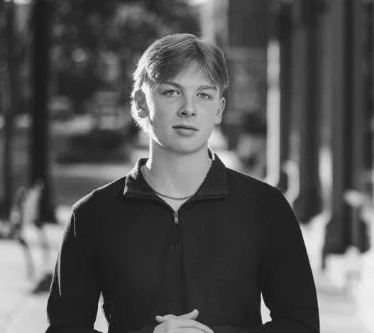 Wyatt Hopkins standing on a sidewalk in a dark quarter-zip, black and white
